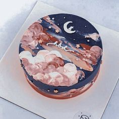 a cake decorated with clouds, stars and the moon is on top of a card