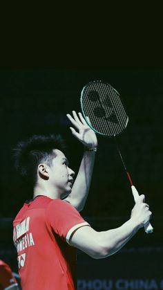 a man holding a tennis racquet on top of a tennis court at night