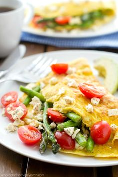 an omelet with asparagus, tomatoes and other vegetables on a plate