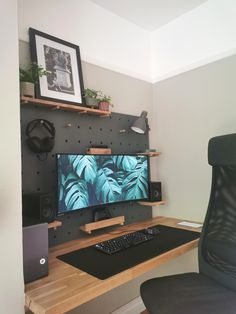 a computer desk with a monitor, keyboard and speakers on it in front of a wall