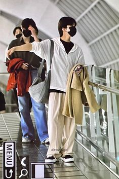 three people are standing on an escalator with their arms around each other and wearing masks