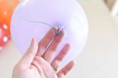 a hand holding a string attached to a balloon