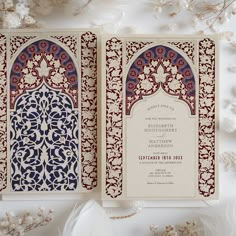 an intricately designed wedding card is displayed on a table with dried flowers and petals