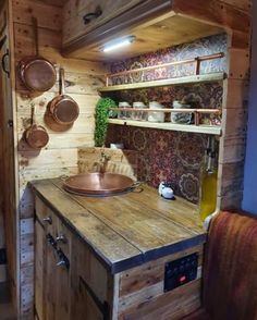 a kitchen area with wooden walls and shelves filled with pots, pans and other items