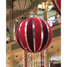 a large red and white ball hanging from the ceiling in a building with lights on it