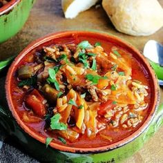 a bowl filled with pasta and vegetables next to bread