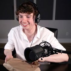 a young man wearing headphones sitting at a desk with a microphone in front of him