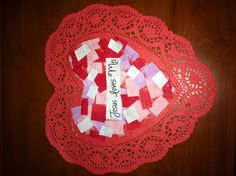 a heart shaped doily that says jesus loves me on it with red and white squares