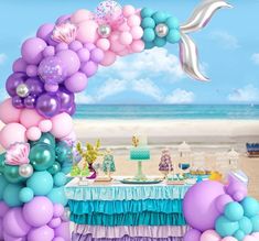 an under the sea themed birthday party with balloons, cake and decorations on the beach