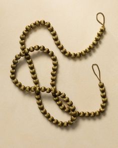 two brass beads are on a white surface and one has a knot at the end