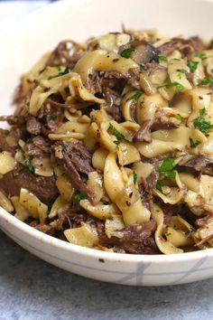 a white bowl filled with pasta and beef