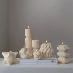 white candles sitting on top of a book next to each other