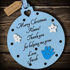 a blue christmas ornament hanging on a wooden wall with the words merry christmas alam thank you for helping me grow