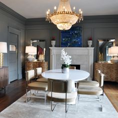 a dining room table with chairs and a chandelier hanging from the ceiling above it