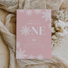 a pink card with white snowflakes on it next to a bouquet of flowers