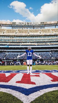 a football player standing on top of a field in front of a stadium filled with people