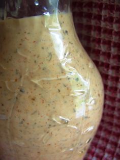 a jar filled with dressing sitting on top of a checkered tablecloth covered table