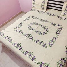 a bed with purple flowers on it in a room that has pink walls and white flooring