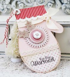 a pink christmas stocking with a white tree in the corner and a red ribbon on top