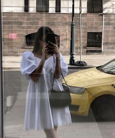 a woman is taking a selfie in front of a window with her cell phone