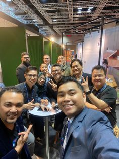 a group of people sitting around a table posing for the camera with their thumbs up