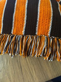 an orange, black and white crocheted pillow with fringes on the edge