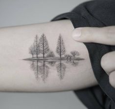 a woman's arm with trees and water on it