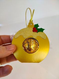 a hand holding an ornament with a gold bauble hanging from it