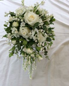 a bouquet of white flowers and greenery on a bed