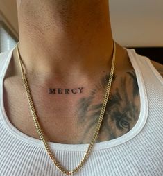 a man with a tattoo on his chest wearing a gold chain and a white t - shirt