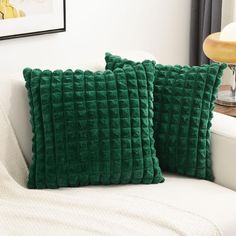 two green pillows sitting on top of a white couch