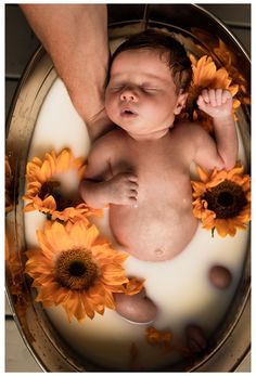 a baby in a tub with sunflowers on the bottom and water around it