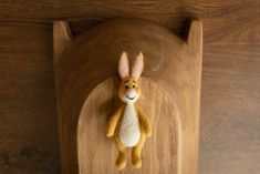 a stuffed animal hanging from the side of a wooden wall mounted on a wood frame