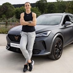 a woman standing next to a grey car