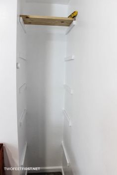 an empty closet with some shelves on the wall and a yellow object in the corner