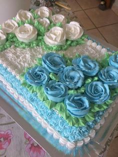 a cake with blue and white frosting roses on it sitting on a counter top