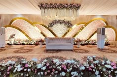 an elaborately decorated stage with couches and flower arrangements on the floor for a wedding reception