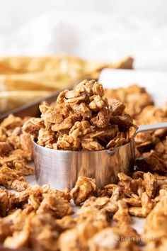 a metal bowl filled with granola sitting on top of a table next to french fries