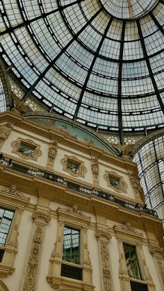 the inside of a building with many windows and glass roof covering it's ceiling