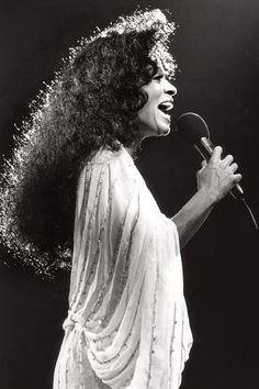 an old photo of a woman singing into a microphone with her hair blowing in the wind