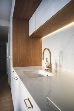 a kitchen with white counter tops and gold faucets