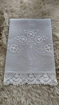 a white doily with flowers on it sitting on top of a fluffy rug next to a window