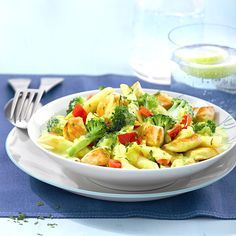 a white bowl filled with pasta and broccoli on top of a blue table cloth