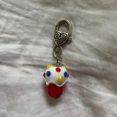 a cupcake shaped keychain is on a white sheet with a heart in the middle