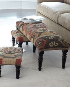 an ottoman and foot stool in a living room with white carpeted flooring on the floor