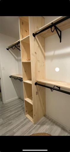 an empty walk in closet with wooden shelves and black brackets on the wall next to it