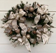 a christmas wreath hanging on the side of a white building with silver and gold decorations