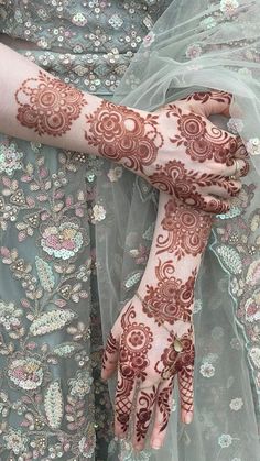 a woman's hands with hennap on her arm and hand covered in flowers