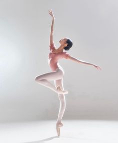 a ballerina in white tights is doing a ballet move with her arms outstretched