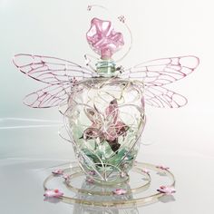 a glass bottle with pink flowers in the shape of a fairy's wings on top